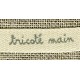Beige ribbon printed grey lettering: Woven Hand